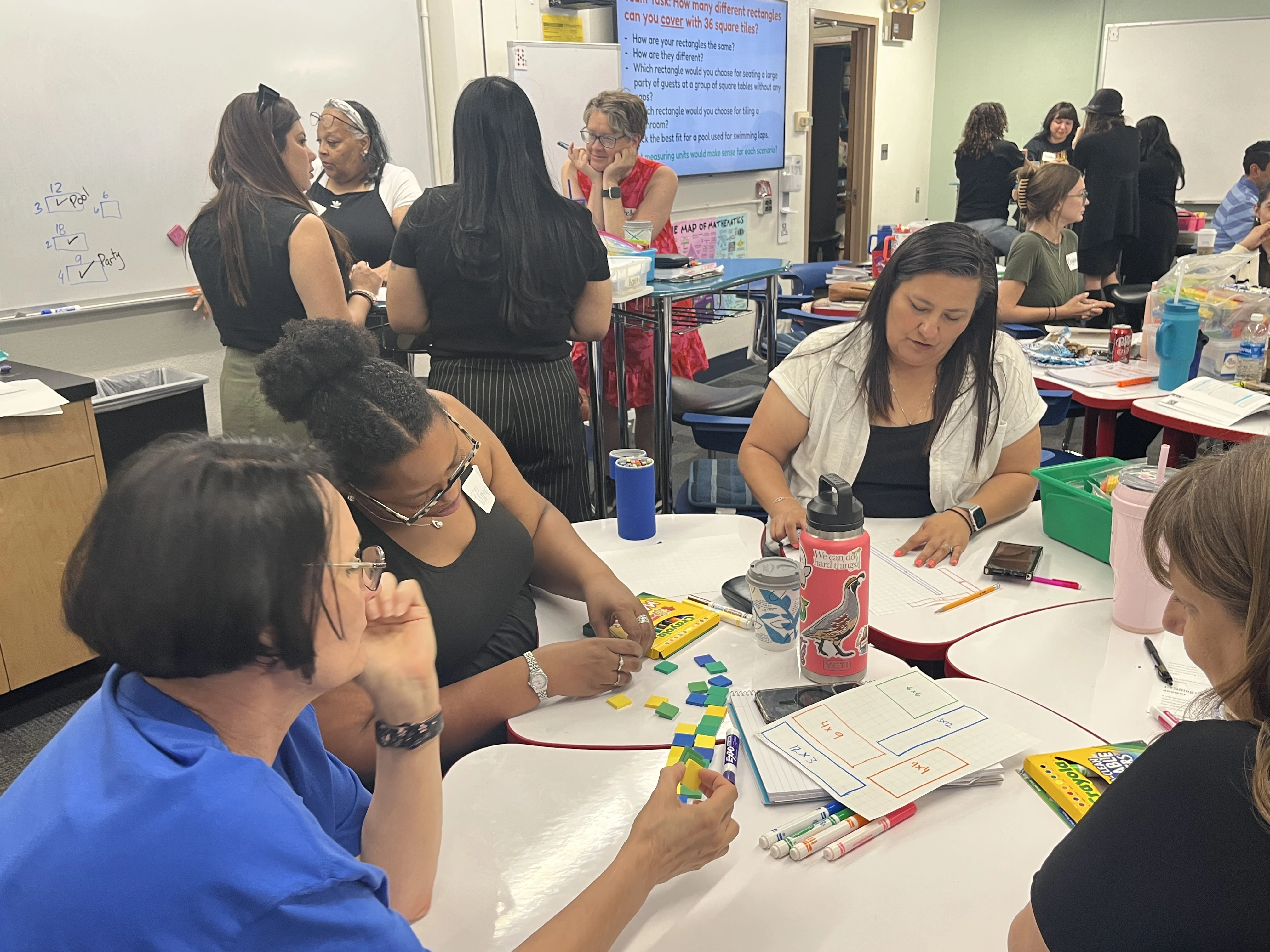 Several Groups working with manipulatives and on whiteboards